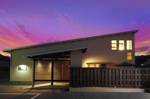 A modern building with a garage entrance, a covered patio, and a wooden fence.