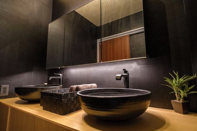 A modern bathroom with a large mirror, two sinks, and a potted plant.