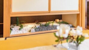 Un meuble en bois doté d’un présentoir intégré, aménagé comme un jardin miniature avec des roches, des plantes et des objets décoratifs.