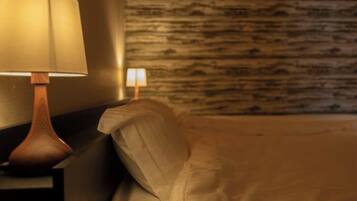 A bed with a headboard, a nightstand with a lamp, and a wall with a textured pattern.