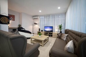 A modern living room with a sofa, coffee table, TV, and a plant. - Loh Residence@Pinjistation (8pax 4br) (Ipoh)