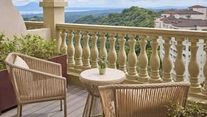 Un balcón con mobiliario de mimbre y vistas a un paisaje montañoso.