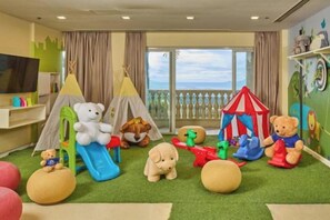 Une salle de jeux pour enfants avec des tentes, un toboggan et divers jouets.