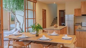 Een moderne keuken met houten kastjes, een centraal eiland en een eethoek met houten stoelen en een tafel voor vier personen.