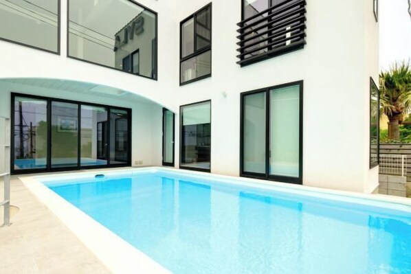 Un edificio moderno con piscina, ampie finestre e tetto piatto.