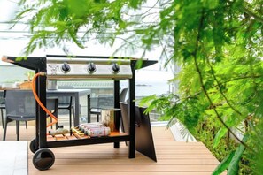 A portable grill on a wooden deck with a view of the ocean. - Syla Hotel Pool Villa (Yokosuka)