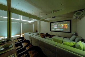 A modern living room with a sofa, a dining table, and a flat-screen TV mounted on the wall. - Syla Hotel Pool Villa (Yokosuka)