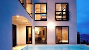 Un immeuble moderne à plusieurs étages, avec une piscine en premier plan.