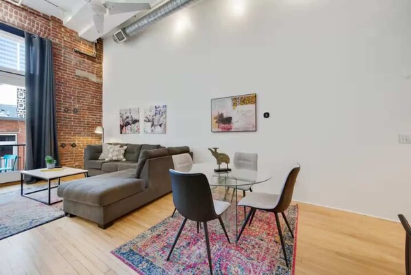 Un salon moderne avec un canapé, des fauteuils, une table en verre et des œuvres d’art accrochées aux murs.