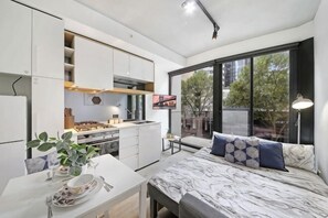 A modern bedroom with a bed, bedside table, and a large window.