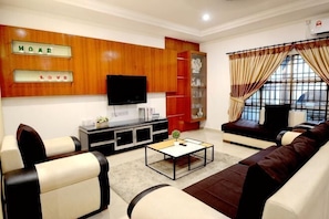 A living room with a sofa set, a coffee table, a TV, and a cabinet with a sign. - Decozy 3.0 Semi-D (18pax++) (Ipoh)