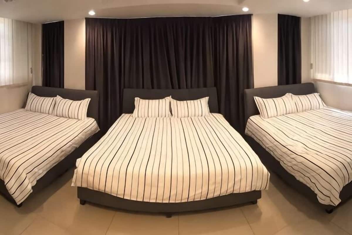 Ein Hotelzimmer mit drei Betten, dunklen Vorhängen und modernem Design.
