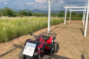 Un cuatrimoto rojo estacionado en un camino de tierra con un letrero blanco.