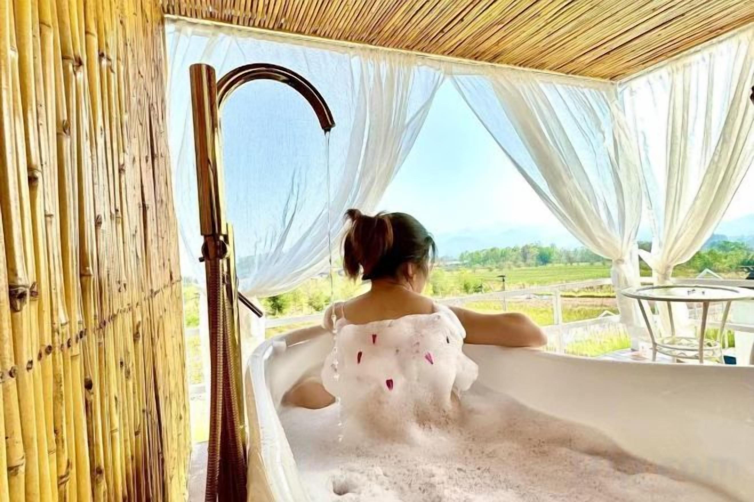 A person in a bathtub with a view of the outdoors.