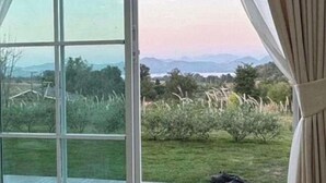 Een kamer met een groot raam, met uitzicht op een grasachtig landschap en verre bergen.