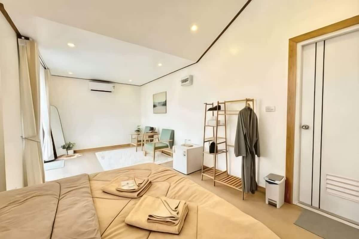Una habitación de hotel moderna con una cama, un escritorio, una silla, un armario y un espejo.