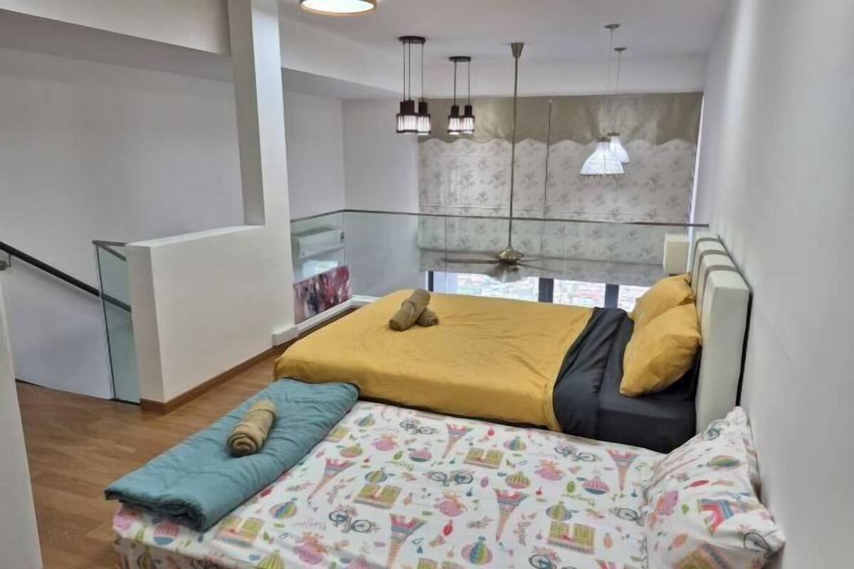A bedroom with a bed, a window, a staircase, and a glass railing.