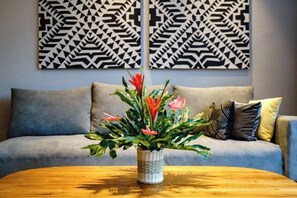 Un salon avec un canapé, une table basse et un vase rempli de fleurs.