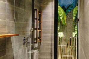 A modern shower with a glass enclosure, a wooden shelf, and a view of aquatic plants. - Casa Tropicale Seminyak (Bali)