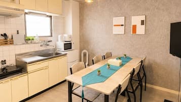 A compact kitchen with a dining area, a microwave, and a TV mounted on the wall.