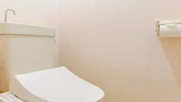 A bathroom with a white toilet, a wall-mounted sink, and a toilet paper holder.