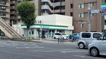 A FamilyMart convenience store at an intersection with a pedestrian crossing, a bicycle, and cars.