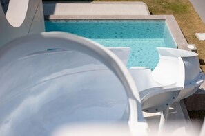 A pool area with a clear blue water surface, a white pool ladder, and a white poolside chair. - Nacha Pool Villa Cha-am (Cha-am)