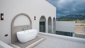 A modern bathroom with a freestanding bathtub, a stone accent wall, and a view of mountains. - Nacha Pool Villa Cha-am (Cha-am)