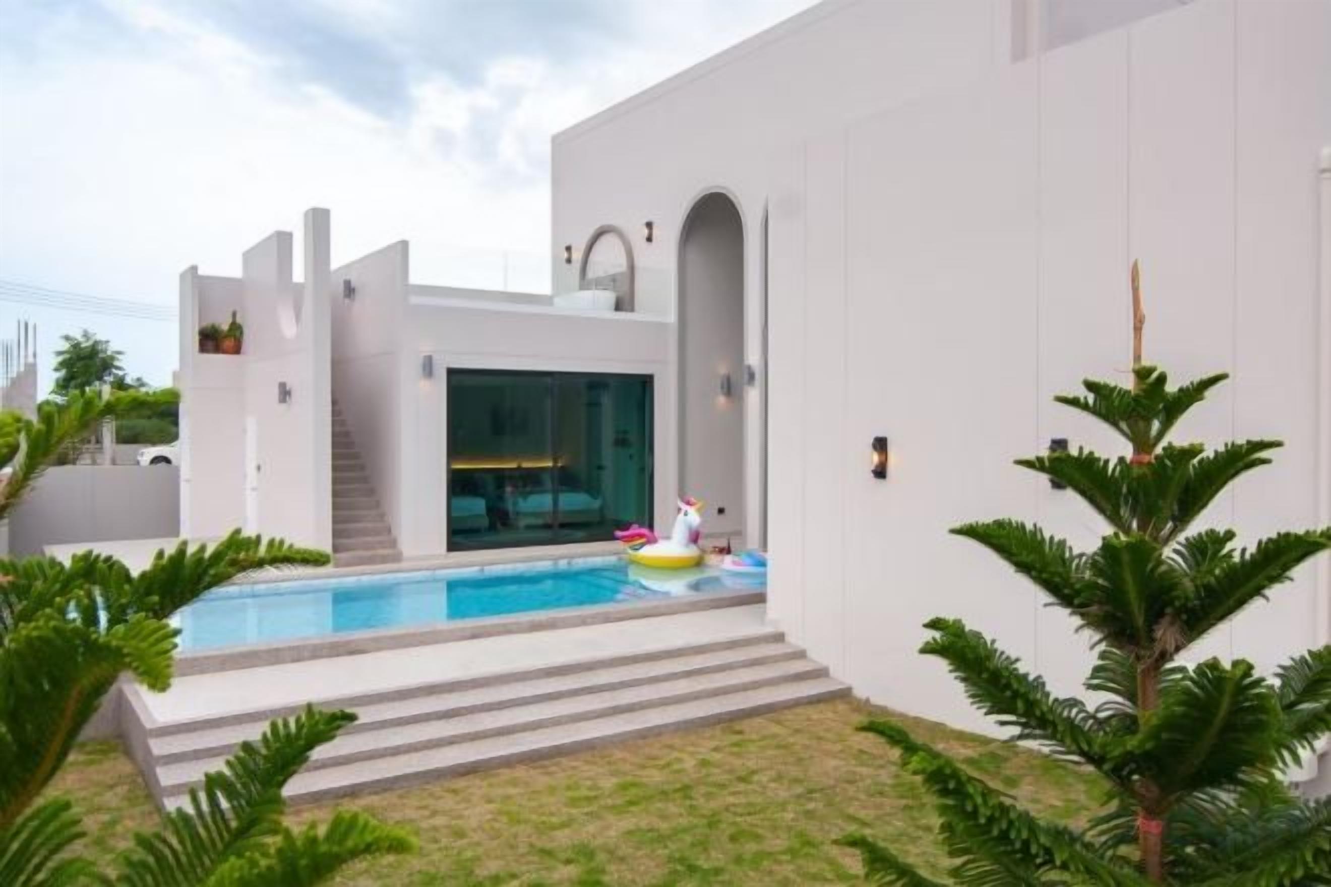 Et moderne hus med swimmingpool, trappe og en velplejet græsplæne.