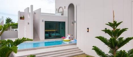A modern house with a swimming pool, a staircase, and a well-maintained lawn.