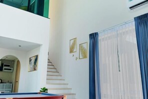 A modern interior with a staircase, a pool table, and a staircase leading to an upper level. - Nacha Pool Villa Cha-am (Cha-am)