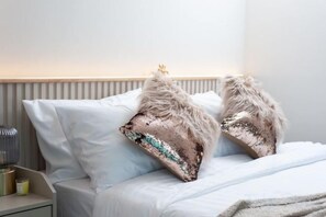 A bed with white linens and two decorative pillows with a sequined design and fluffy accents. - Nacha Pool Villa Cha-am (Cha-am)
