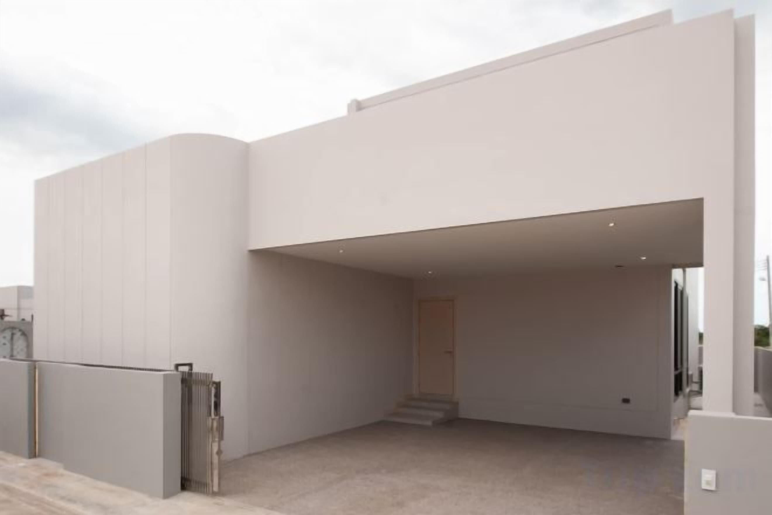 A modern building with a flat roof, a covered entrance, and a staircase leading to an upper level.