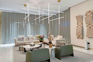 A modern hotel lobby with a sofa set, a coffee table, and a decorative vase. - bnbme Luxurious Canal View Apt w/ Pool & Gym (Dubai)