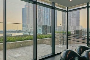 A modern interior with large windows, a view of a river, and a metal railing. - bnbme Luxurious Canal View Apt w/ Pool & Gym (Dubai)