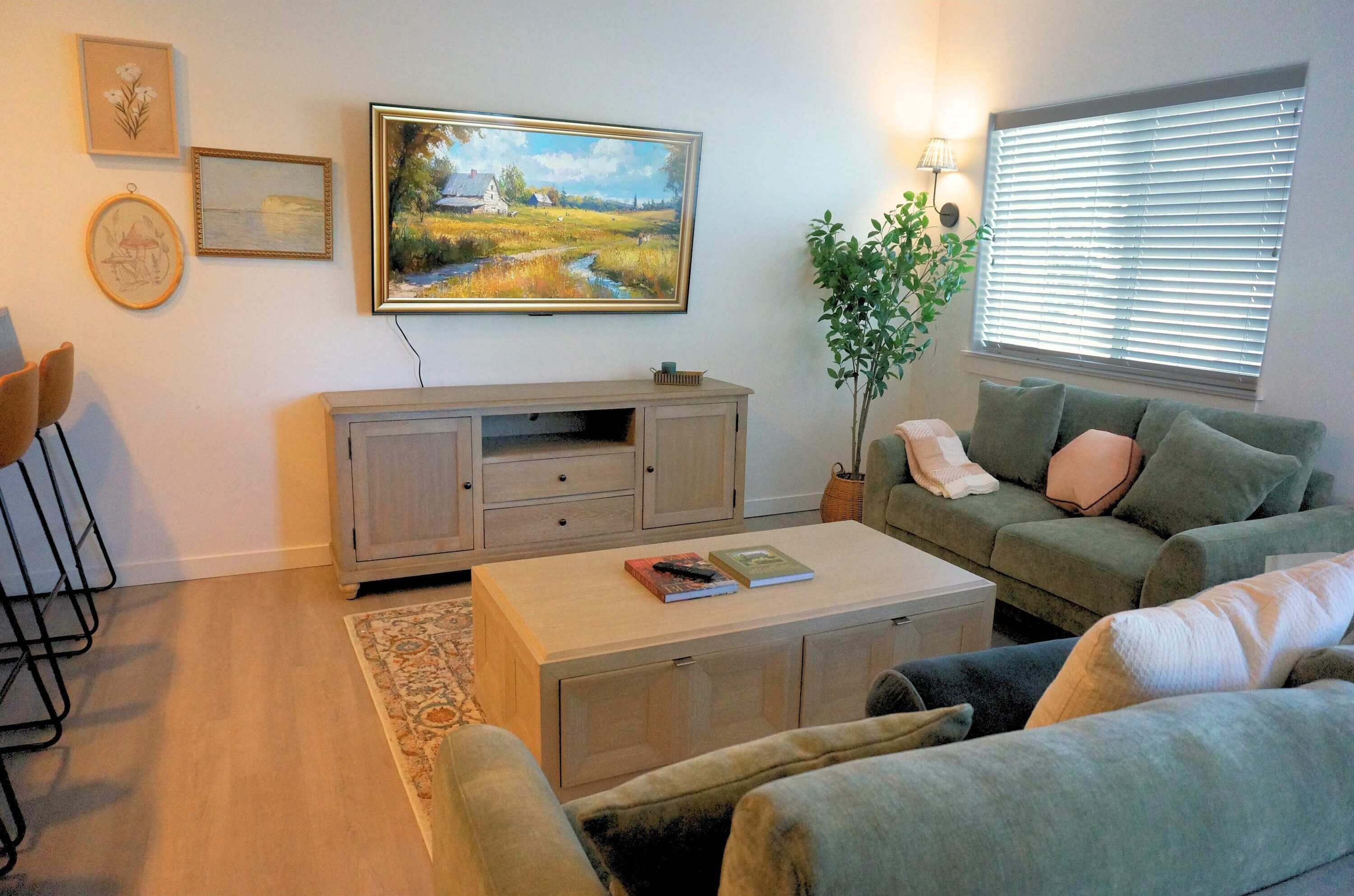 A living room with a sofa, a coffee table, a TV, and artwork on the wall.
