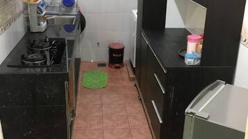 A compact kitchen with a gas stove, sink, and a refrigerator.