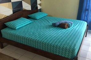 Een bed met een beddengoed met patroon, twee kussens en een opgerolde handdoek.