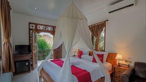 A bedroom with a bed, bedside table, TV, and curtains. - Sekarini Place Amed (Bali)