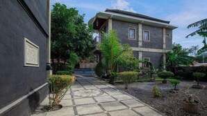 A two-story building with a tiled courtyard, surrounded by greenery and potted plants. - Sekarini Place Amed (Bali)