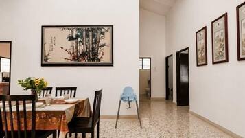 A dining area with a table set for four, chairs, a vase with flowers, and framed artwork on the wall.