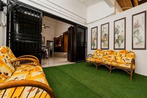 Una habitación con alfombra verde, un sofá y un banco. Hay puertas que dan a otras habitaciones.