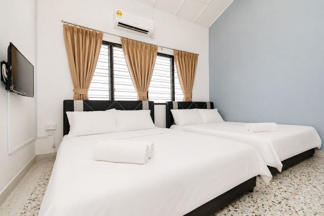 A hotel room with two beds, a flat-screen TV, and an air conditioning unit.