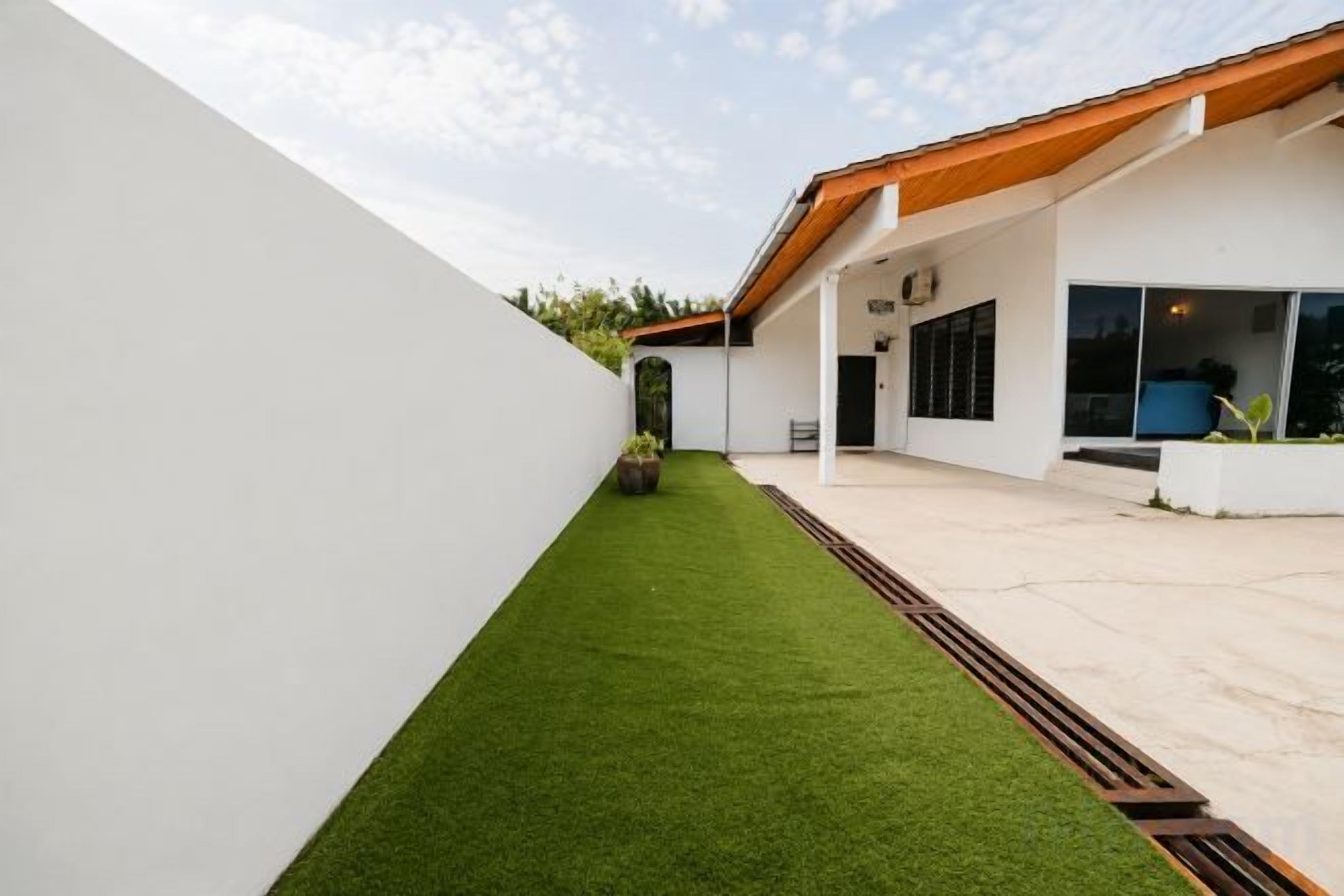 Un edificio moderno con techo plano, patio empedrado y un pequeño espacio con césped.