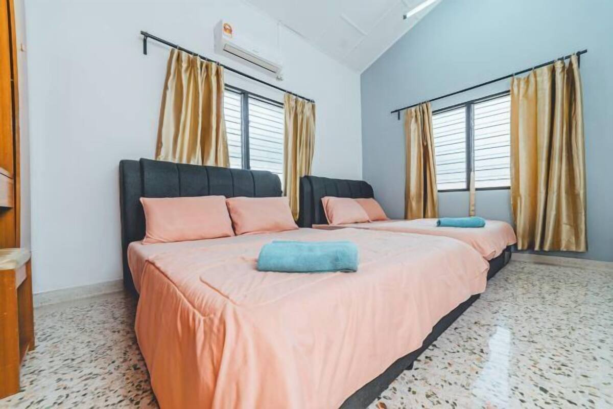 A hotel room with two beds, beige curtains, a window with blinds, and a tiled floor.