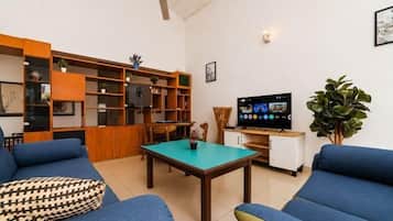 A living room with a sofa, a coffee table, a TV, and a bookshelf.