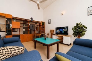 Una sala de estar con un sofá, una mesa de centro, un televisor y una estantería.