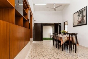 Un pasillo con comedor, paneles de madera, ventilador de techo y una obra enmarcada en la pared.
