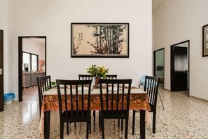 A dining area with a table set for four, a vase with flowers, and a painting on the wall. - Batu Pahat w Pooltable Villa 4Br16Pax by Our Stay (Simpang Kanan)