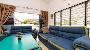 A living room with a blue sofa set, a coffee table with a plant, and a view through a window with blinds.